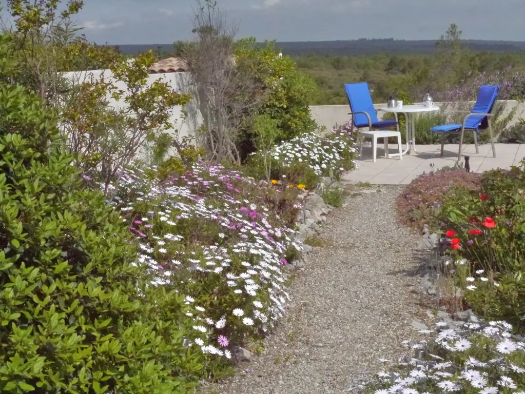 Mediterraner Garten des Ferienhauses in voller Frühlingsblüte mit Sitzplatz