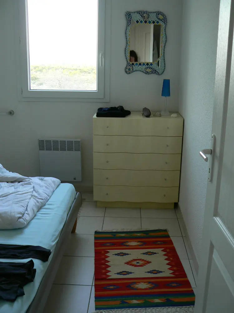 Zweites Schlafzimmer des Ferienhauses mit Doppelbett, Kommode und Blick in die Garrigue